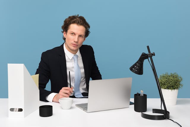 Man Sitting With Laptop Computer on Desk and Lamp