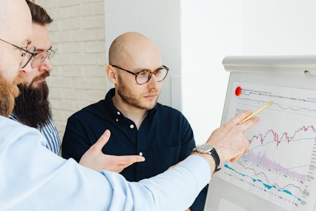 employees wearing eyeglasses looking at the graph on the board