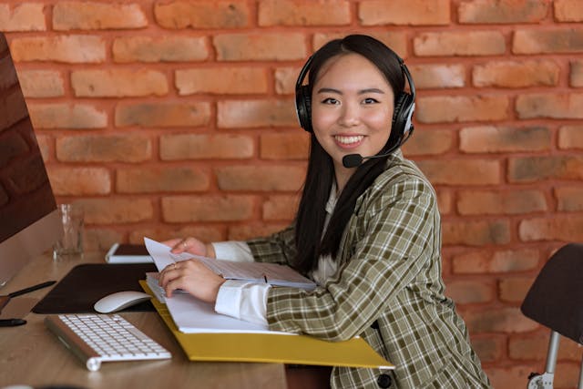 woman in plaid blazer with headset looking at camera